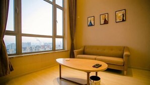 Une pièce avec une grande fenêtre, un canapé, une table et trois tableaux encadrés accrochés au mur.