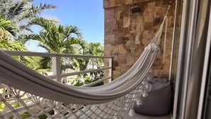 A hammock on a balcony with a stone wall and palm trees in the background. - Posada Libert Hotel (Díaz)