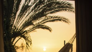 A hammock tied to a balcony railing, overlooking a sunset with palm trees in the background. - Posada Libert Hotel (Díaz)