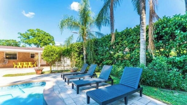 A pool area with lounge chairs and a building in the background. - Relaxing SWEET HOME 9mi Downtown Pool&Hot tub. (Jacksonville)