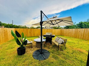 A backyard with a grill, outdoor furniture, and a large umbrella. - Home just minutes from Downtown,Airport’s (Houston)