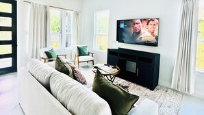 A modern living room with a sofa, chairs, a coffee table, a TV, and a fireplace.