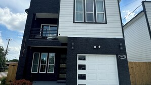 A modern two-story house with a white garage door and a black exterior.