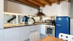 Una cocina moderna con armarios blancos, electrodomésticos de acero inoxidable y un refrigerador azul.