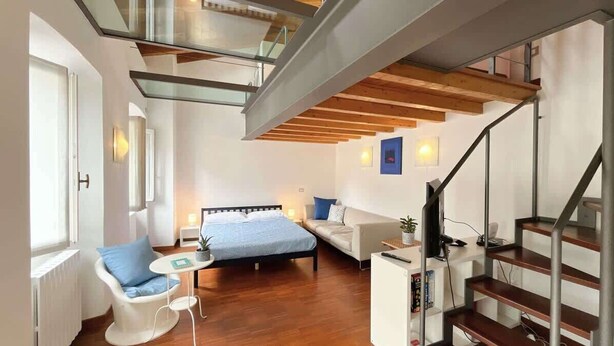 Un dormitorio moderno con cama, sofá, una mesita y una escalera.