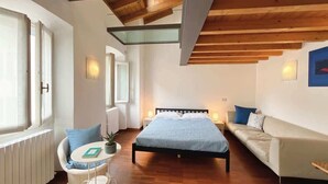 Un dormitorio con cama, sofá, sillón y una mesita.
