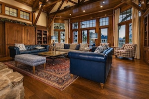 A spacious living room with leather sofas, a coffee table, and a large window with curtains.