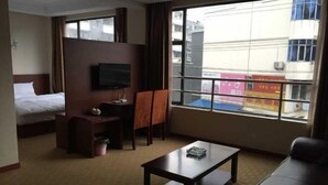 A hotel room with a bed, a desk, a TV, a window, and a view of the outside. - Lido Holiday Hotel (Shitai)