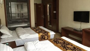 A hotel room with two beds, a television, a desk, and a wardrobe. - Lido Holiday Hotel (Shitai)
