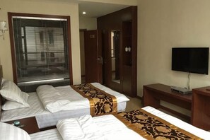 A hotel room with two beds, a television, a desk, and a wardrobe. - Lido Holiday Hotel (Shitai)