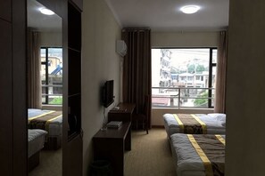 Habitación de hotel con dos camas, un escritorio, un televisor y una ventana con vista a la ciudad.