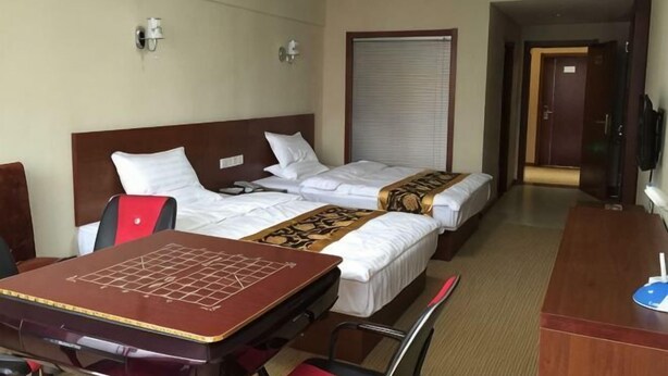 A hotel room with two beds, a desk, and a television. - Lido Holiday Hotel (Shitai)