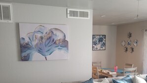Un saló amb un sofà gris, coixinets blaus i blancs, i un quadre abstracte gran a la paret.