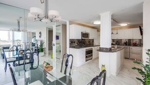 Een moderne keuken met witte kasten, een granieten aanrecht en roestvrijstalen apparatuur.