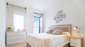 Une chambre à coucher comprenant un lit, des tables de chevet, une commode, une fenêtre avec des rideaux et des œuvres d’art murales.