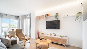Un salon moderne comprenant un canapé, une table basse, un téléviseur et un coin repas avec des chaises et une table.