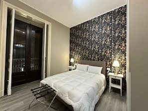 Une chambre à coucher avec un grand lit, une armoire et une table de chevet avec une lampe.