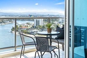 Enjoy breathtaking views of the city from this balcony with a table, chairs, and a potted plant.