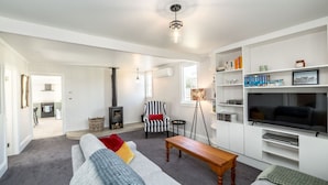 A modern living room with a grey sofa, a wooden coffee table, a striped armchair, and a TV on a white stand.
