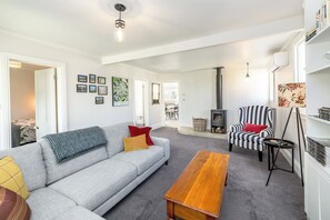 A living room with a sofa, a striped armchair, a wooden coffee table, a fireplace, and a bookshelf.
