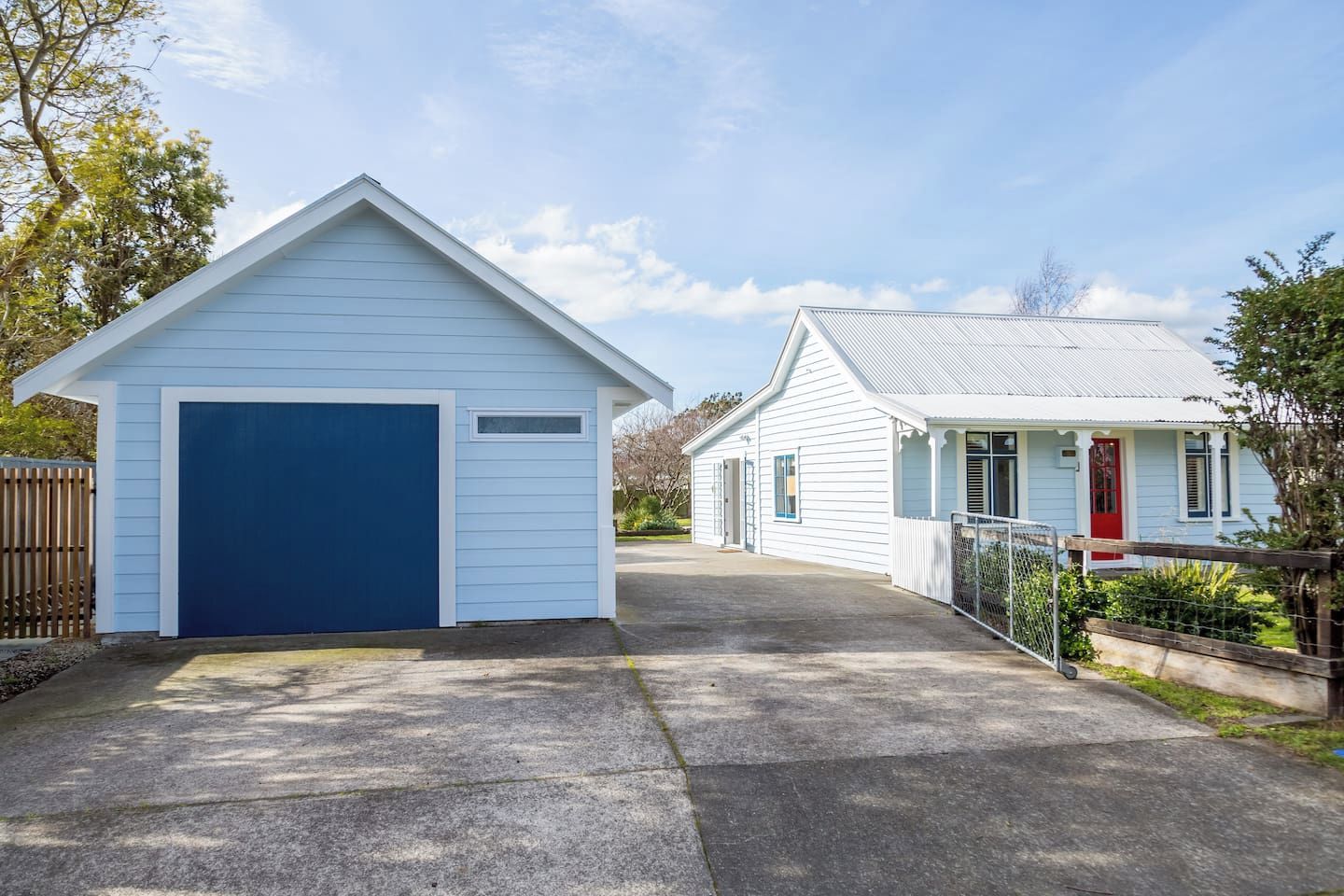 A residential property with a garage, a covered porch, and a red door.