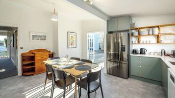 A modern kitchen with a stainless steel refrigerator, wooden cabinets, and a dining area with a table and chairs.