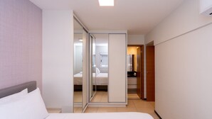 Una habitación de hotel con una cama, un acceso corredizo al baño y un pequeño escritorio con silla.
