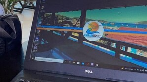 A laptop displaying a hotel website with a tropical beach view. - Enseada Hostel (Arraial do Cabo)