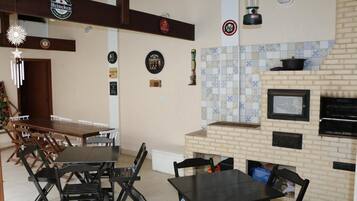 A dining area with a brick fireplace, a television, and a hanging lantern.