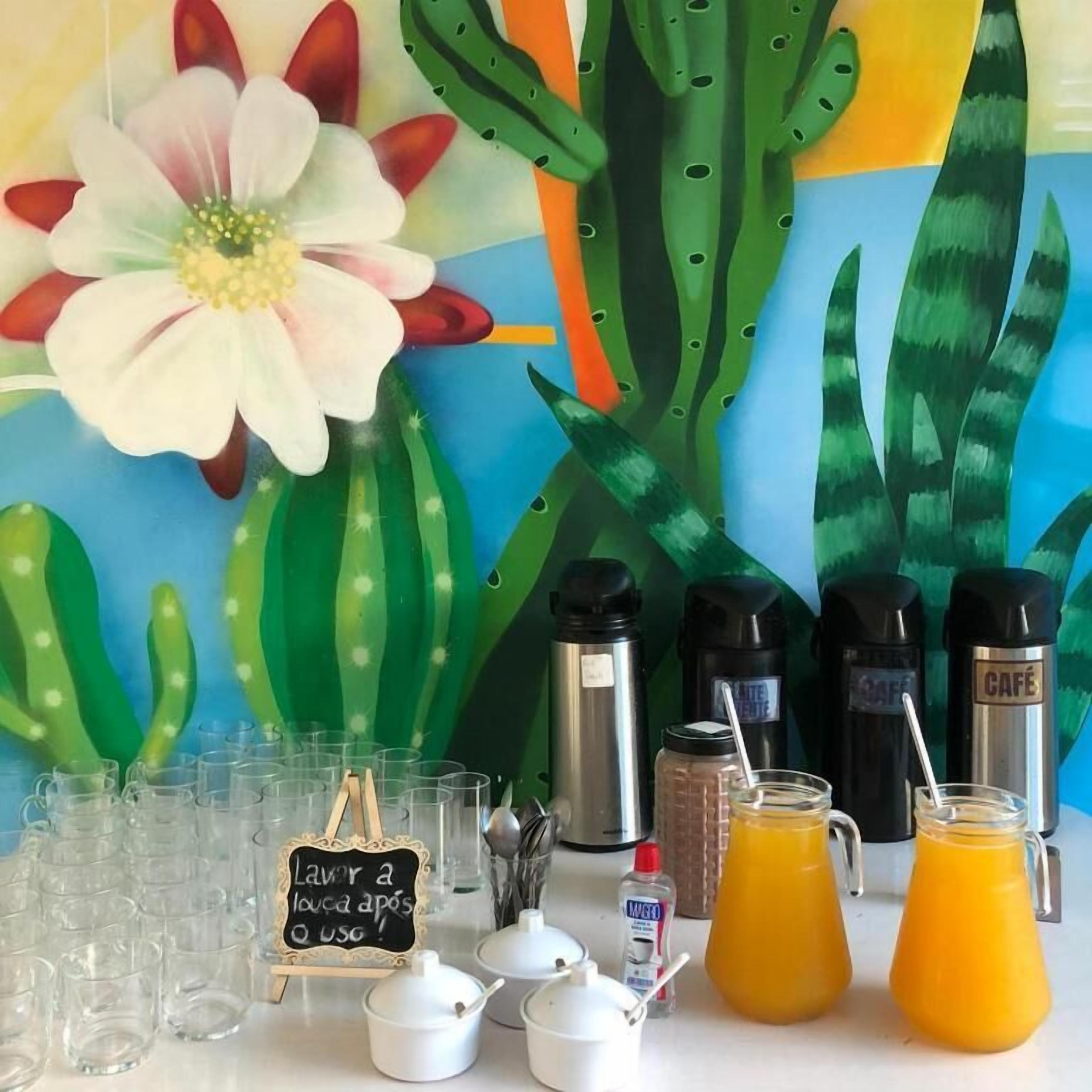 A breakfast setup with coffee makers, a sign, and a pitcher of orange juice.