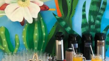 A breakfast setup with coffee makers, a sign, and a pitcher of orange juice.