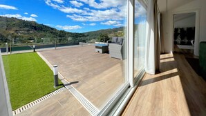 A spacious balcony with a view of a green landscape and hills.