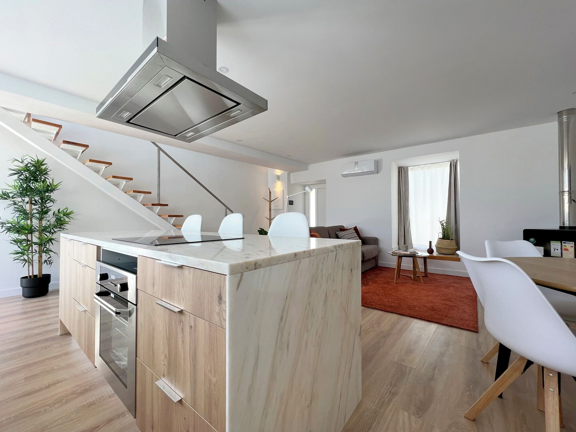 Une cuisine moderne dotée d’un îlot central, de meubles en bois et d’une hotte de cuisine en acier inoxydable.