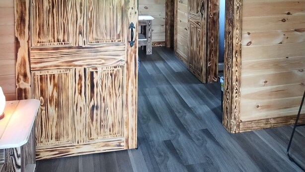 Ein rustikal eingerichtetes Zimmer mit Holzelementen, ausgestattet mit einer großen Holztür und einer Bank im Hintergrund.