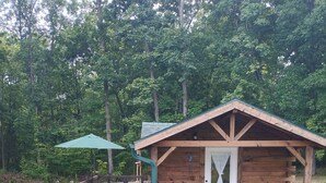 Eine Holzhütte mit Veranda, überdachter Sitzgelegenheit und kleiner Terrasse.