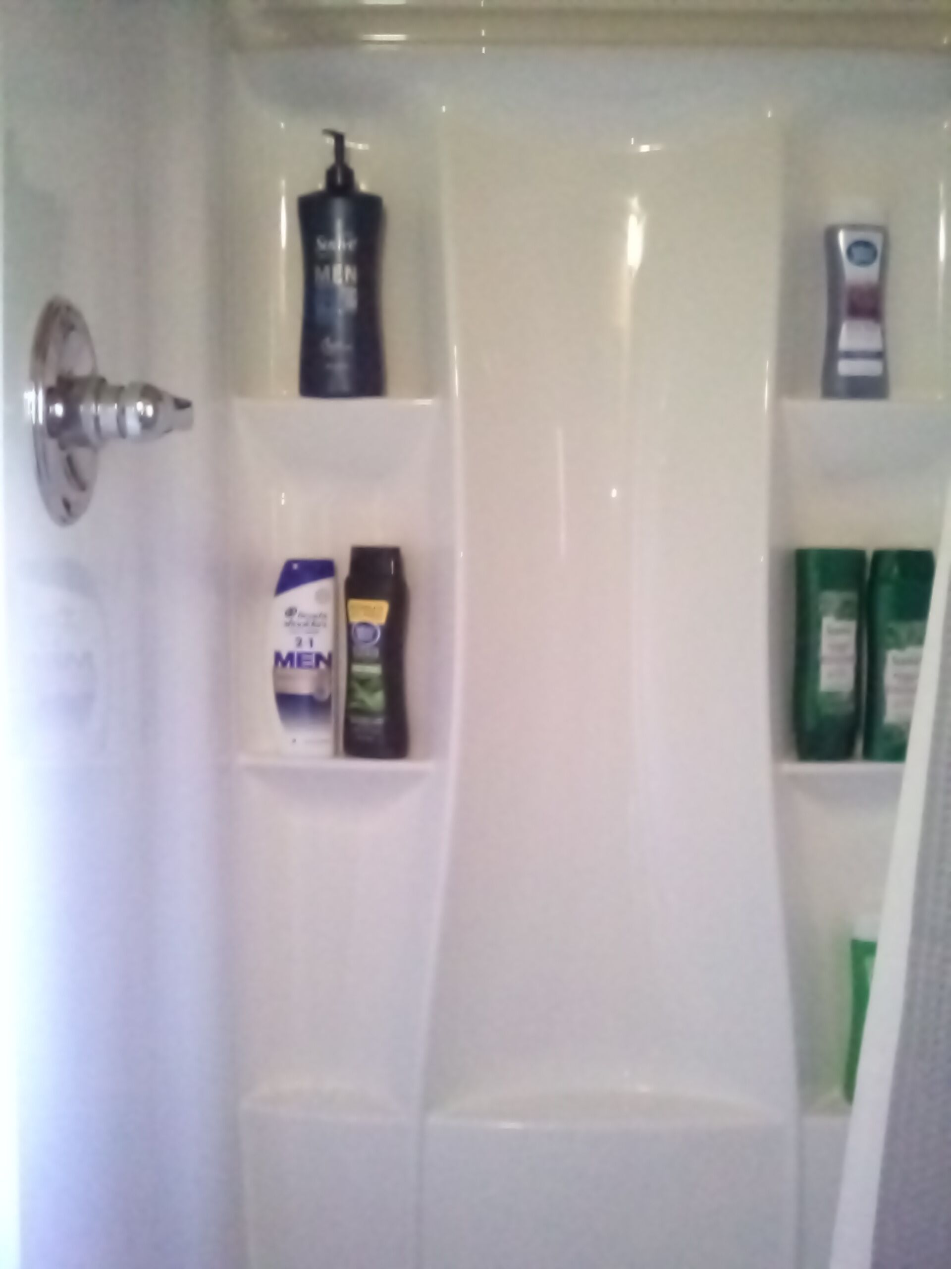 A bathroom with a white sink, a mirror, and shelves holding toiletries including a bottle labeled "MEN" and green bottles.