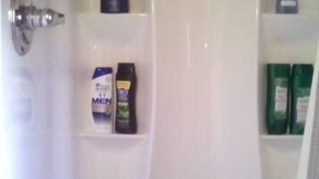 A bathroom with a white sink, a mirror, and shelves holding toiletries including a bottle labeled "MEN" and green bottles.