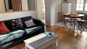 A living room with a sofa, a coffee table, and a dining area with chairs and a table. - Pretty, quiet vacation home with wooded garden  (Perigny)