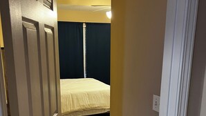 A narrow hallway leading to a bedroom with a bed, a wooden floor, and a ceiling fan. - Near ACOM and hospital , 2-bedroom house in charming Dothan with WiFi, AC.  (Dothan)
