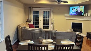 A dining area with a table set for six, a sofa, a television, and a fireplace. - Near ACOM and hospital , 2-bedroom house in charming Dothan with WiFi, AC.  (Dothan)