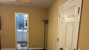 A hallway with a wooden floor, a white door, and a bathroom visible through an open door. - Near ACOM and hospital , 2-bedroom house in charming Dothan with WiFi, AC.  (Dothan)