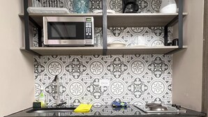 Une cuisine compacte équipée d’un four à micro-ondes, d’une machine à café et d’un petit réfrigérateur.