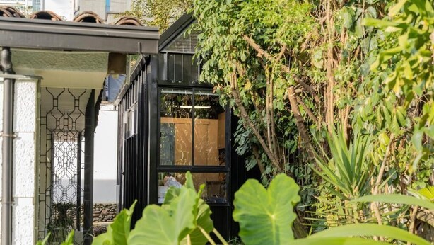 Un bâtiment moderne à la façade noire, avec une porte en verre donnant sur une pièce.