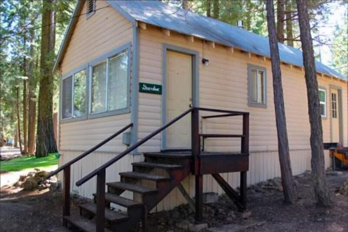 Una pequeña cabaña de madera con porche, escaleras y un letrero que dice 'Ski Lodge'.
