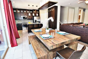 A modern kitchen with dark wooden cabinets, stainless steel appliances, and a wooden dining table set for four. - Entrada at Moab 425 (Moab)