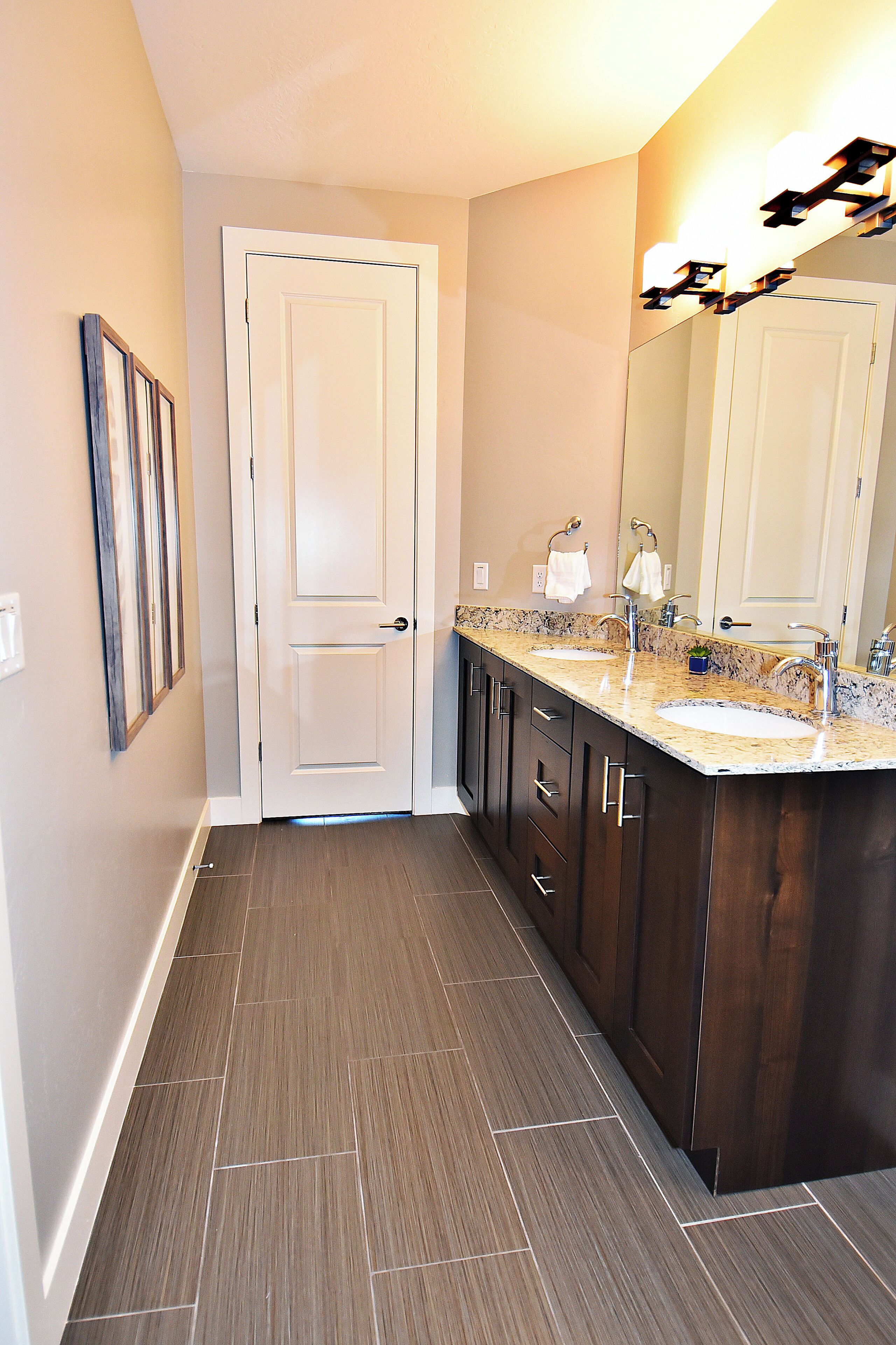 A bathroom with a double sink vanity, dark wood cabinets, and a large mirror.