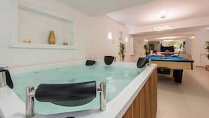 Un espace piscine comprenant un jacuzzi, une table de billard et une table de jeu de fléchettes.
