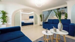 Un salon moderne avec un canapé bleu, une table basse et un escalier menant à une autre pièce.