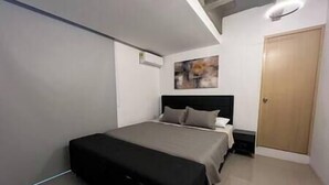 A bedroom with a bed, a nightstand, a door, and a painting on the wall. - The Aragon El Poblado Lofts Triplex w/Penthouse (Medellín)