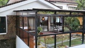 A modern house with a glass extension, stone walls, and a visible interior with a sofa and lamp. - The Provenza Mansion by Lleras Park in El Poblado (Medellín)